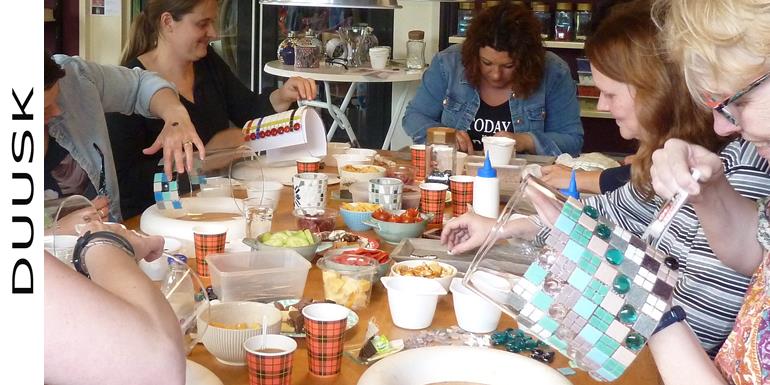 Tijdens dit vrijgezellenfeest zitten er 8 dames een mozaiek lamp workshop te realiseren. Ze hebben nootjes, chips op de tafel staan
terwij er gezellig wordt geklets.